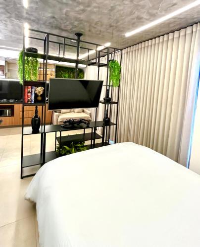 a bedroom with a white bed and a television at Lindo flat em prédio luxuoso - Excelente localização in Goiânia