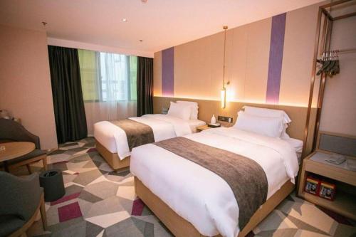 a hotel room with two beds and a table at Lavande Hotel Shenzhen East Gate Wanxiang City Guomao Metro Statipn in Shenzhen