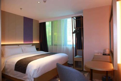 a bedroom with a bed and a table and a chair at Lavande Hotel Shenzhen East Gate Wanxiang City Guomao Metro Statipn in Shenzhen