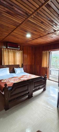 a large bed in a room with a wooden ceiling at Banasura Green paradise , Villa , Deluxe rooms , Budget rooms in Padinjarathara