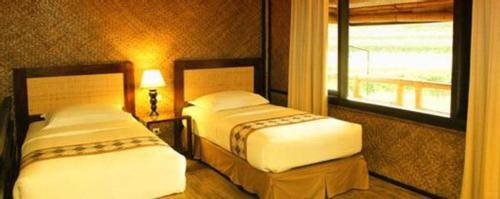 two beds in a hotel room with a window at Sambi Resort, Spa & Resto in Yogyakarta