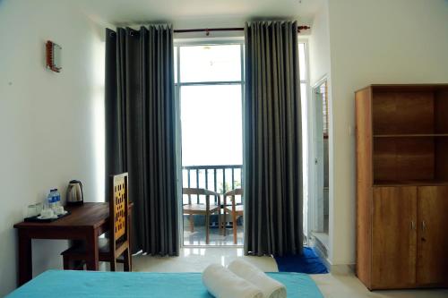 a bedroom with a bed and a desk and a window at Cocos in Midigama