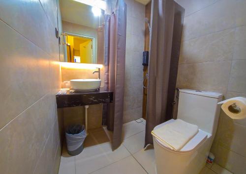 a bathroom with a white toilet and a sink at Abell Hotel in Kuching