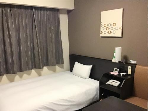 a hotel room with a bed and a window at Hotel Route Inn Hashimoto in Hashimoto