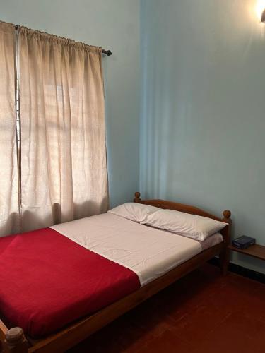 a bed with a red blanket and a window at Fog view cottage - Homestay with food and internet in Vythiri