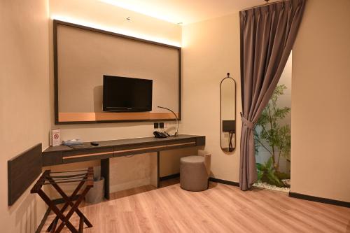 a hotel room with a tv and a desk with a television at Abell Hotel in Kuching