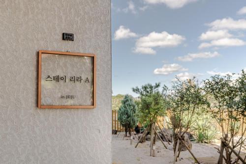 a sign on the side of a building with trees at Jeju Stayra in Jeju