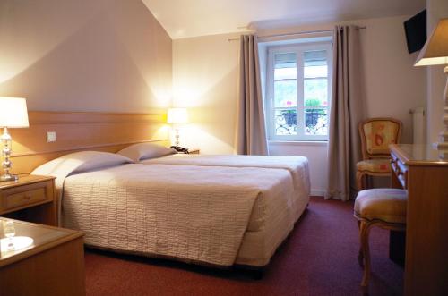 a hotel room with a bed and a window at Hôtel Le Roosevelt in Givet