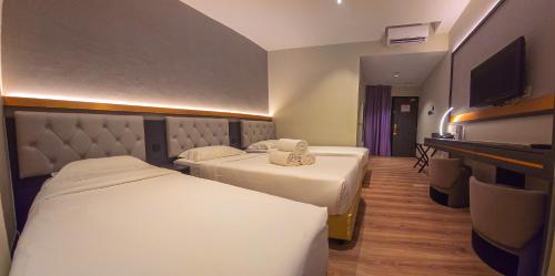 a hotel room with two beds and a television at Abell Hotel in Kuching