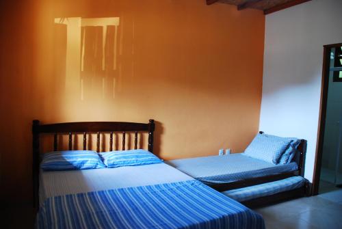 a bedroom with two beds and a chair at Chalés na Mata Ubatuba in Ubatuba