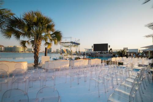 a group of white chairs and a table and palm trees at Hilton Abu Dhabi Yas Island in Abu Dhabi