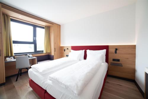 a large white bed in a room with a window at Best Western Hotel Tulln in Tulln
