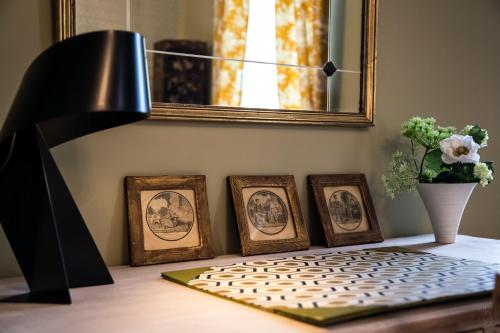 a table with four framed pictures and a lamp at Le Clos Tellier in Mareil-Marly