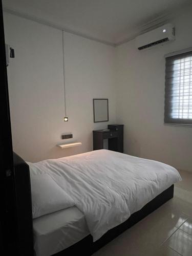 a bedroom with a white bed and a window at 23 Inn Queenbed Room with share bathroom in Simpang Ampat