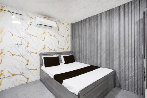 a small bedroom with a bed and a stone wall at Hotel O Kadodara Surat Sanjivani Hospital Formerly Rolex in Balesar