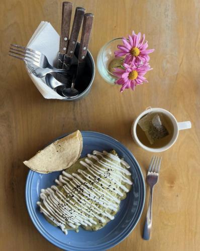 a plate of food on a table with a fork and a flower at Suites Lassa in Ensenada