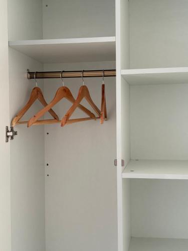 a closet with wooden hangers in a white room at Thira House in Varkala