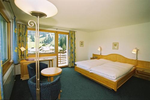 Schlafzimmer mit einem Bett, einem Tisch und einem Fenster in der Unterkunft Hotel Alpina Parpan in Parpan
