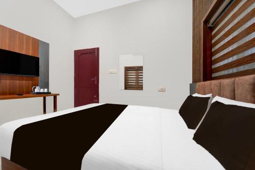 a bedroom with a large white bed and a red door at Super Townhouse Thondayad Calicut Formerly Dream Casa in Kakkayam