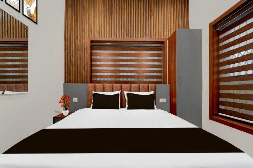 a bedroom with a large white bed with a wooden headboard at Super Townhouse Thondayad Calicut Formerly Dream Casa in Kakkayam
