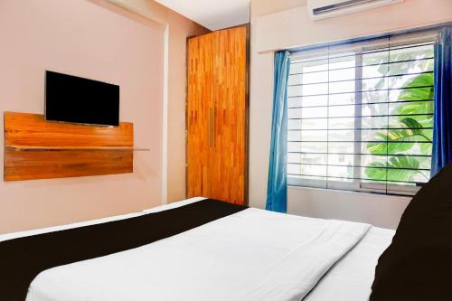 a bedroom with a bed with a television and a window at Super Collection O Khatri Park Formerly Aum Villa in Lonavala