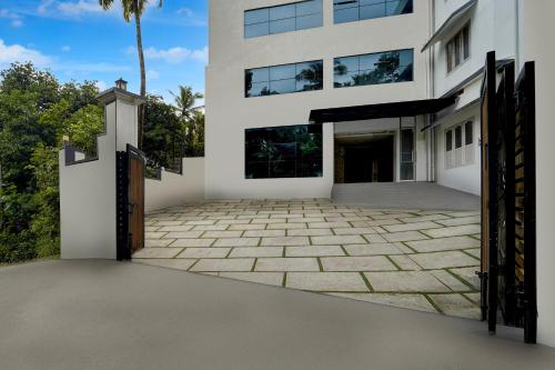 an exterior view of a white building with a driveway at Super Townhouse Thondayad Calicut Formerly Dream Casa in Kakkayam