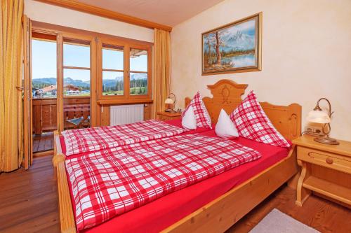 a bedroom with a bed with a red and white blanket at Winklmoos Sonnenalm in Reit im Winkl