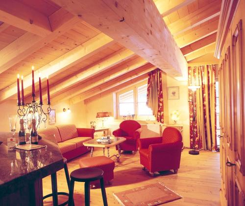 a living room with wooden ceilings and red chairs at Winklmoos Sonnenalm in Reit im Winkl