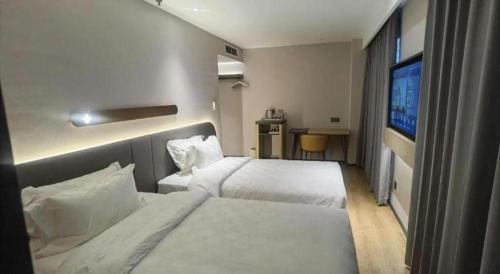 a hotel room with two beds and a television at Jinjiang Inn Tianjin Station Jinwan Square in Tianjin