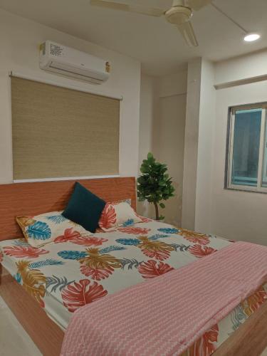 a bedroom with a large bed with a flowered blanket at Staeg Nirvana 2BHK in Indore