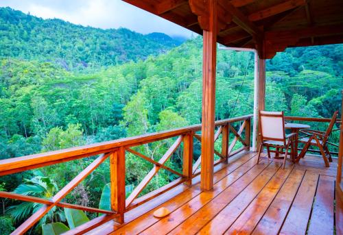 a porch with two chairs and a table on a mountain at Villa Vanilla in Port Glaud