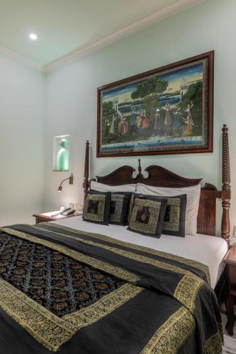 a bedroom with a large bed with a painting on the wall at Rajasthan Palace - A Heritage Boutique Hotel in Jaipur in Jaipur