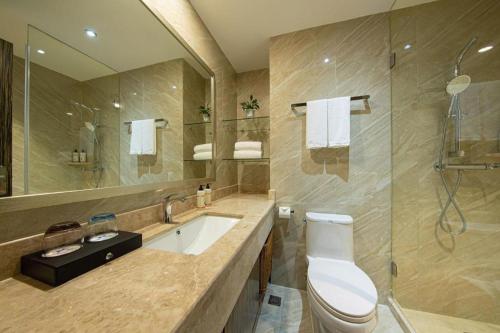 a bathroom with a sink and a toilet and a mirror at Landmark Hotel in Zhuhai