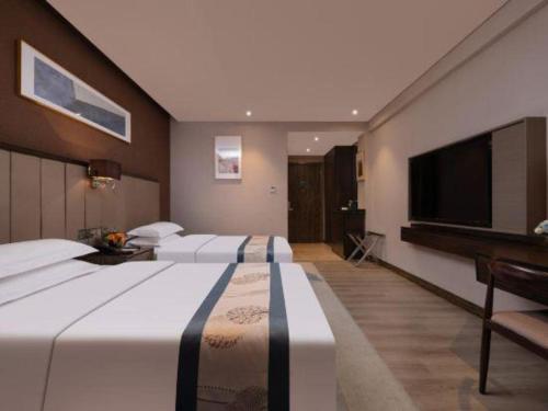 a hotel room with two beds and a flat screen tv at Landmark Hotel in Zhuhai