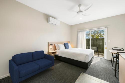 a bedroom with a bed and a blue couch at Avenue WEST Studio Units in Toowoomba