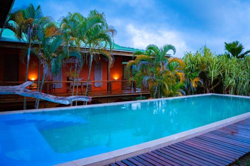 a swimming pool in front of a house with palm trees at Villa Vanilla in Port Glaud