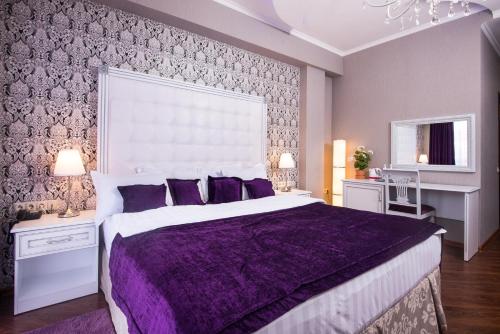 a purple bedroom with a large bed with purple pillows at Hotel De Paris in Krasnodar