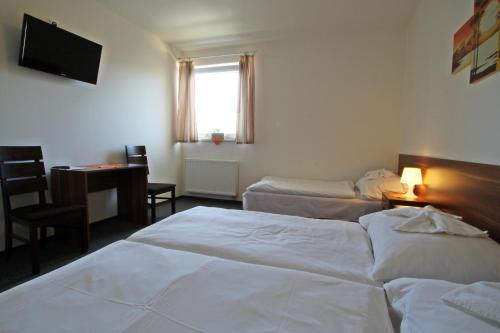 a hotel room with two beds and a desk and a television at Penzión Pagy in Višňové