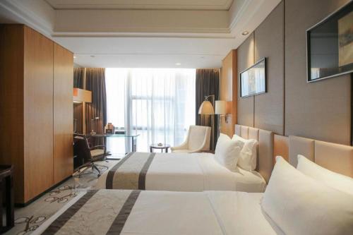 a hotel room with two beds and a desk at Zhangjiagang Zhonglian GDH International Hotel in Zhangjiagang