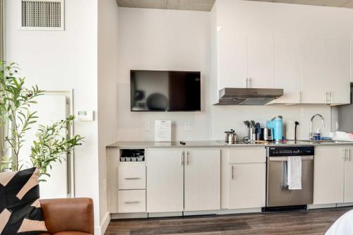 a kitchen with white cabinets and a tv on the wall at Boulevard Stays Highrise STU Sky Pool Parking Gym 19 in Phoenix