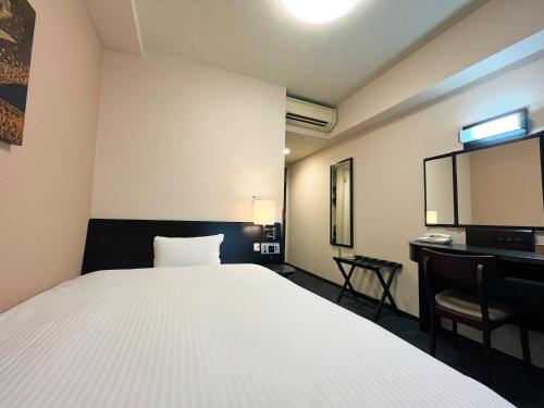 a bedroom with a white bed and a desk at Hotel Route-Inn Hofu Ekimae in Hofu