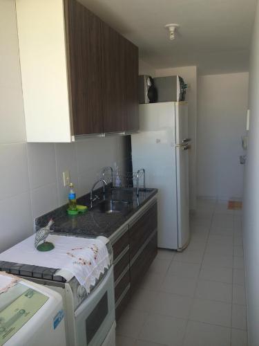 La cuisine est équipée d'un évier et d'un réfrigérateur blanc. dans l'établissement Apartamento Guarapari com aconchego, à Guarapari
