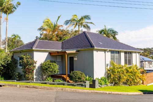 a house on a street with palm trees at Idyllic 4-Bed Home With Alfresco Area Near Beach in Deewhy