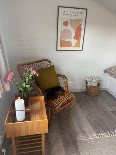 a living room with a chair and a table with a candle at FF1006 Autentisk Feriebolig i Hemmet med adgang til pool in Hemmet