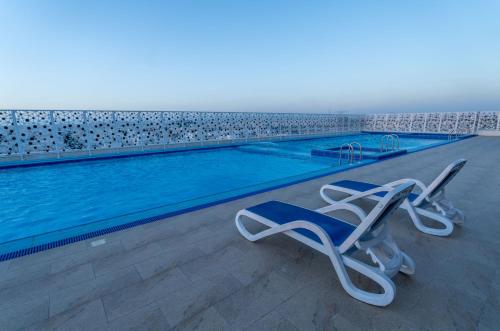 a swimming pool with two lounge chairs in front of it at Sunday Jeddah Hotel in Jeddah