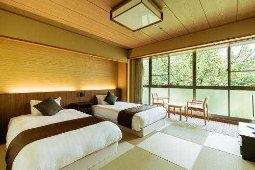 a bedroom with two beds and a table and chairs at KAMENOI HOTEL Arima in Kobe