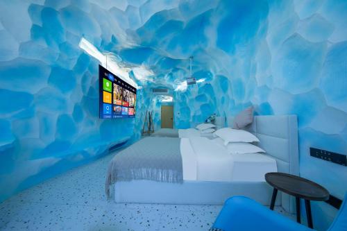 a bedroom with a bed in a blue room at Caroline Designer Hotel, Gaozhuang, Xishuangjing in Jinghong