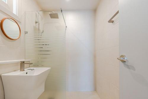 a white bathroom with a sink and a shower at Jeju Stayra in Jeju