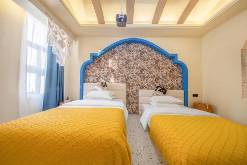 two beds in a room with yellow and blue at Caroline Designer Hotel, Gaozhuang, Xishuangjing in Jinghong