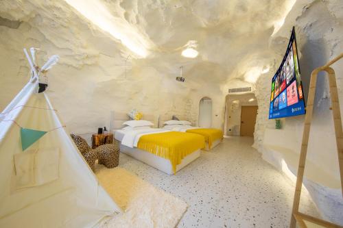 a bedroom with two beds and a tv in a cave at Caroline Designer Hotel, Gaozhuang, Xishuangjing in Jinghong